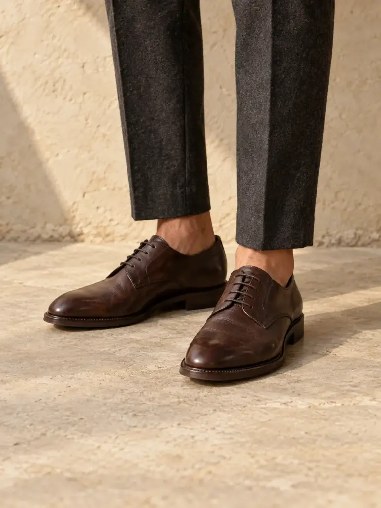 Man wearing dark brown leather derby shoes and charcoal trousers